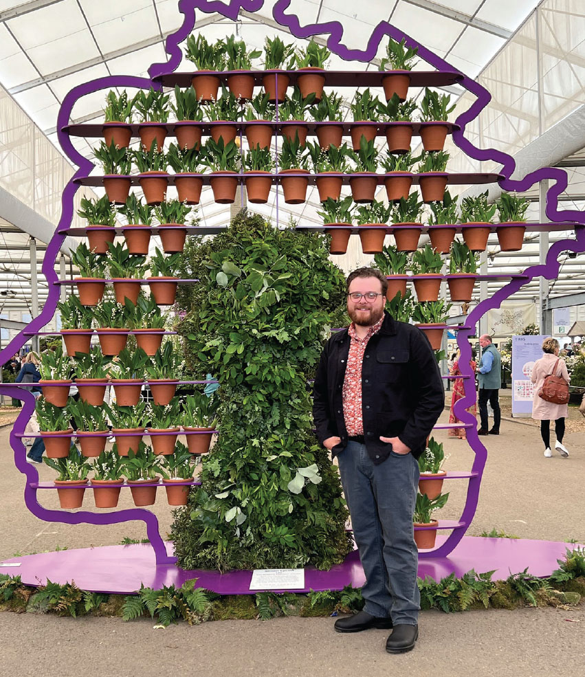 Connor Schmit standing in front of a shelf of plants.