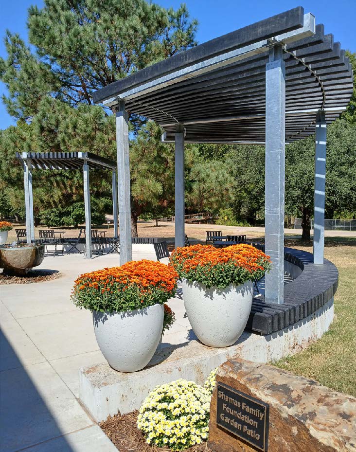 An outdoor covered patio with two white pots of orange flowers that is next to a plaque.