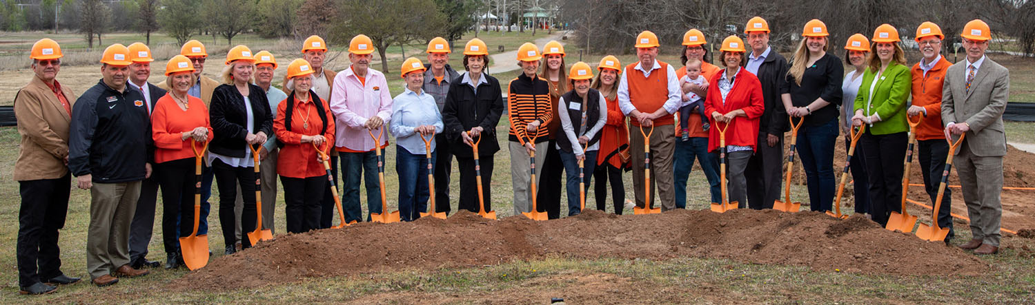 A group of people lined up with a orange shovel and a orange hard hart.
